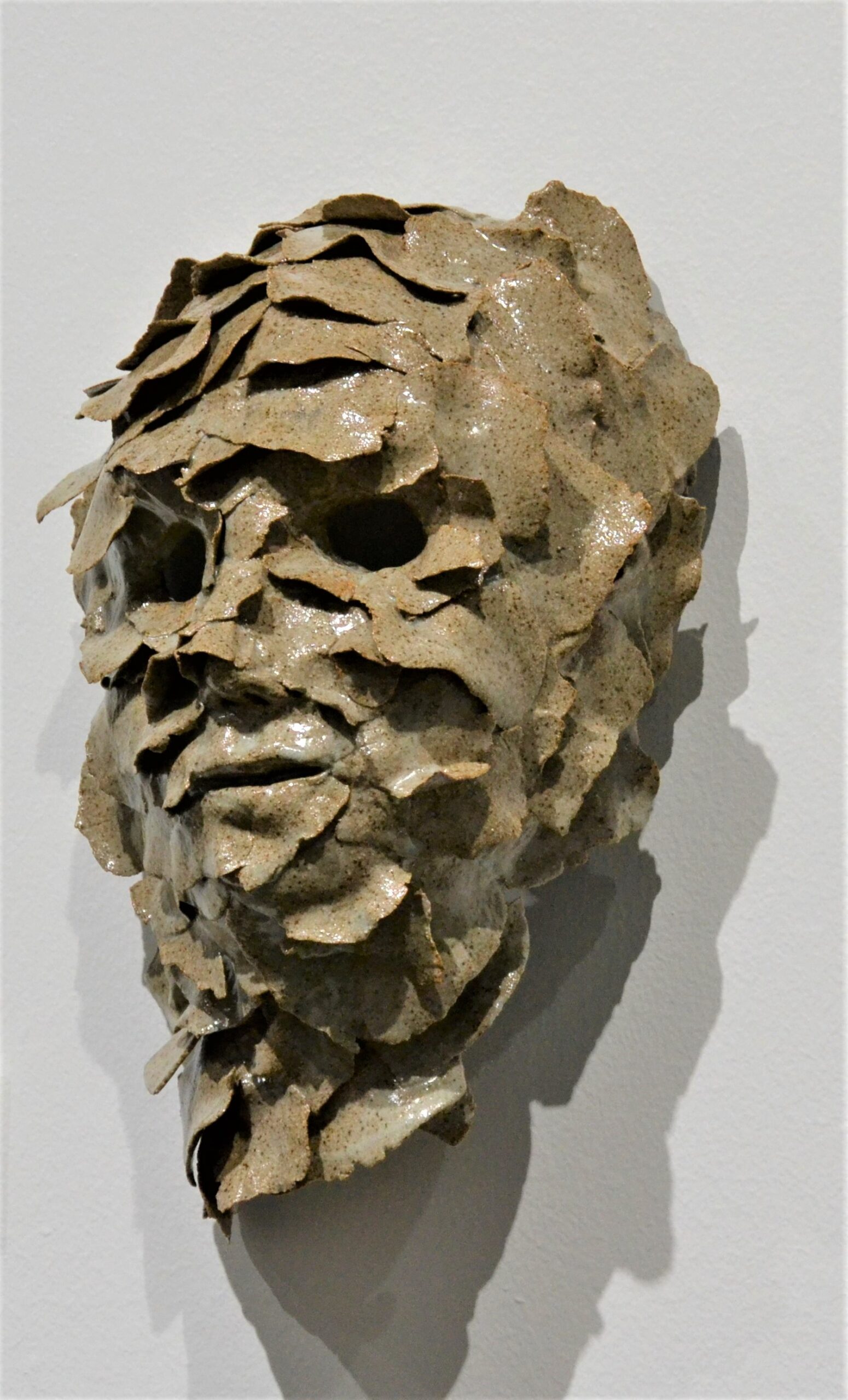 Ceramic art sculpture of a head and face full of layers that look like scales